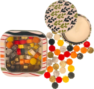Botanical Mix sealing wax pearls by Holly Heide in red, orange, yellow, green and metallic colors with decorative storage tin and candle.