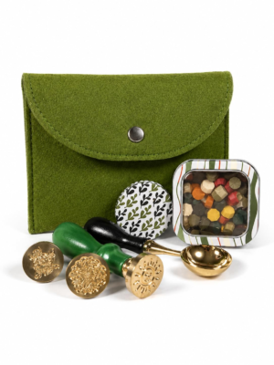 Holly Heide Moss Green Wax Seal Kit with green felt pouch, three brass wax stamps, colorful wax pearls, candle tin, and gold pouring spoon.